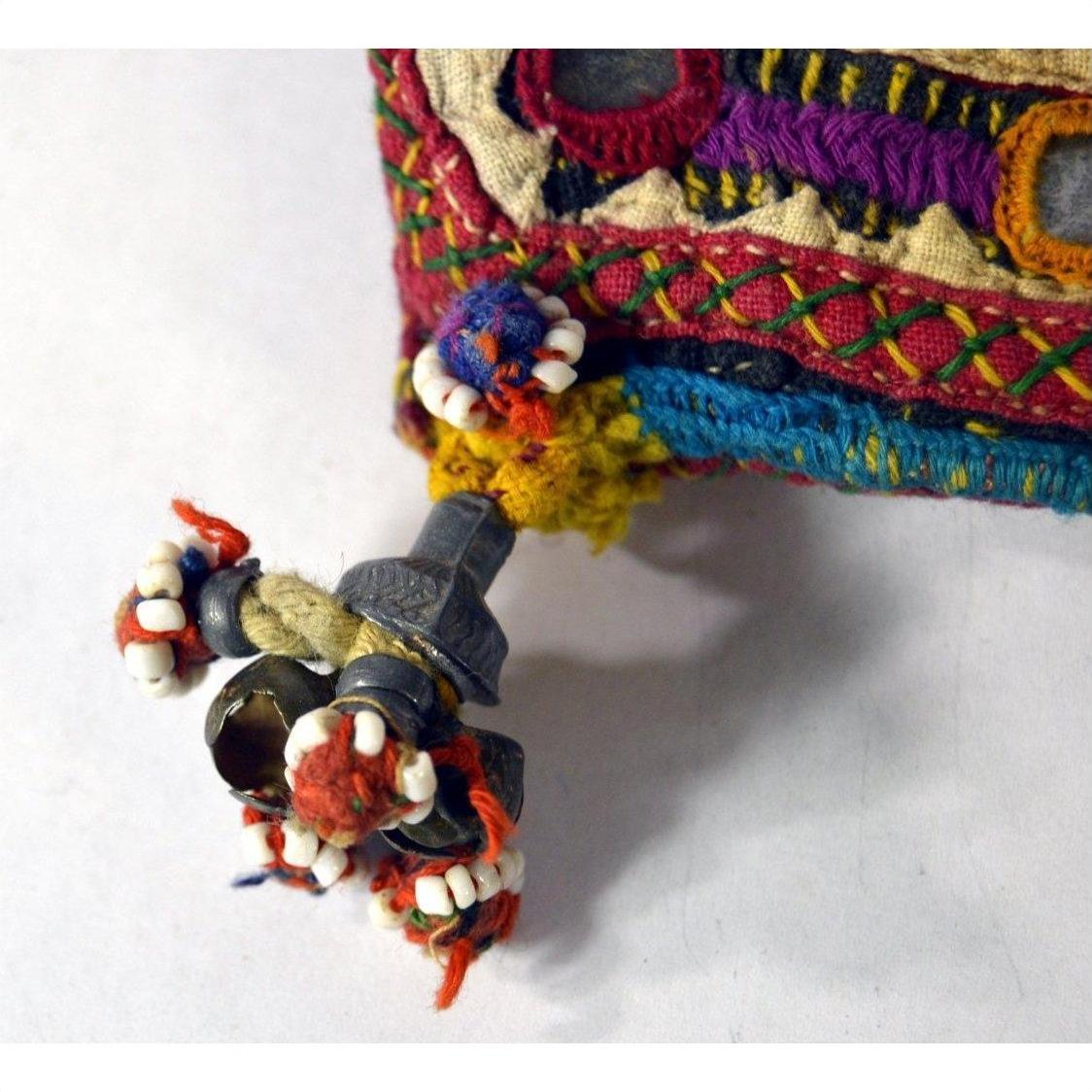 Colorful fabric pouch with traditional Indian embroidery, metal trinkets, and beads on a white background.