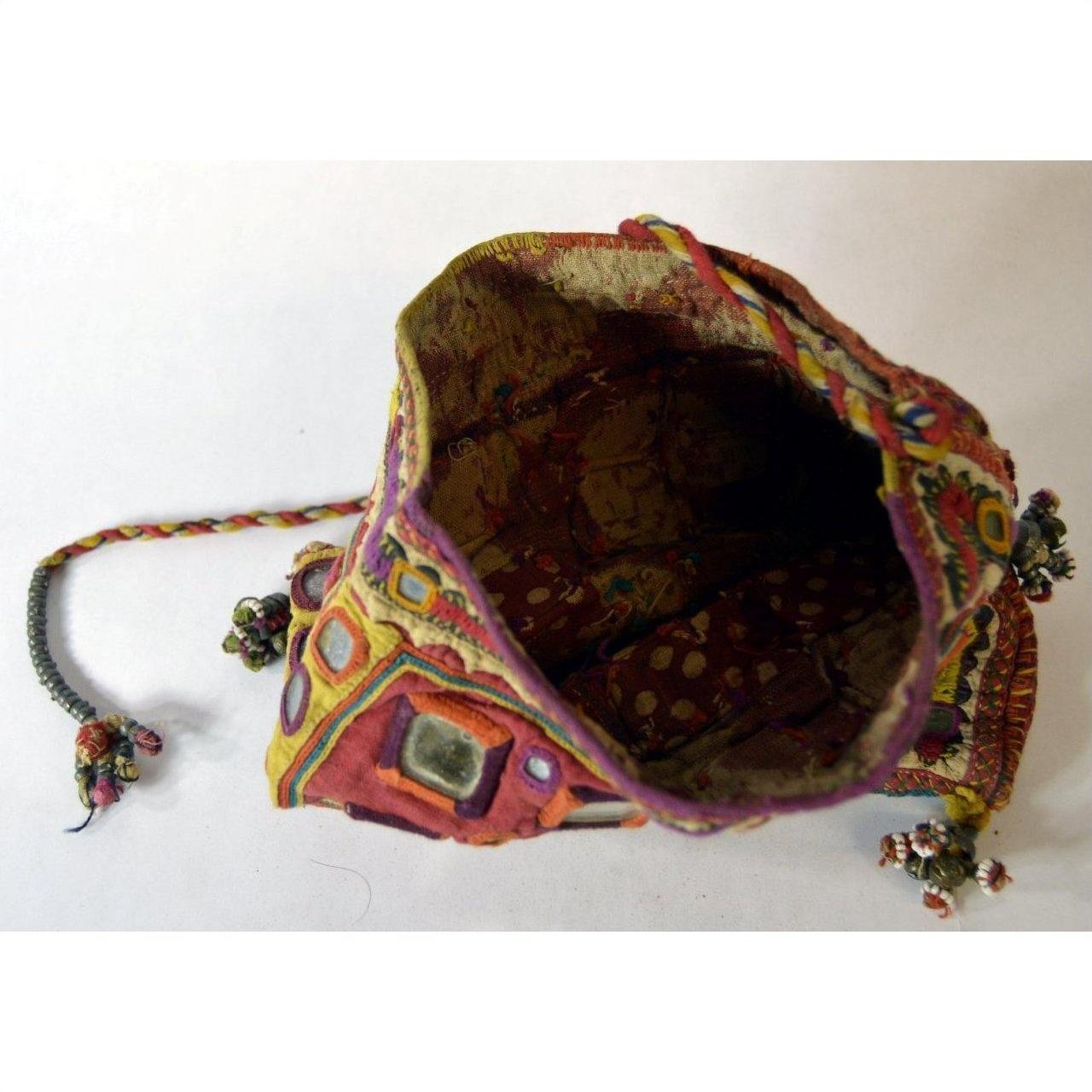 Multicolored embroidered fabric pouch with geometric patterns and mirrors, drawstring closure, top view.