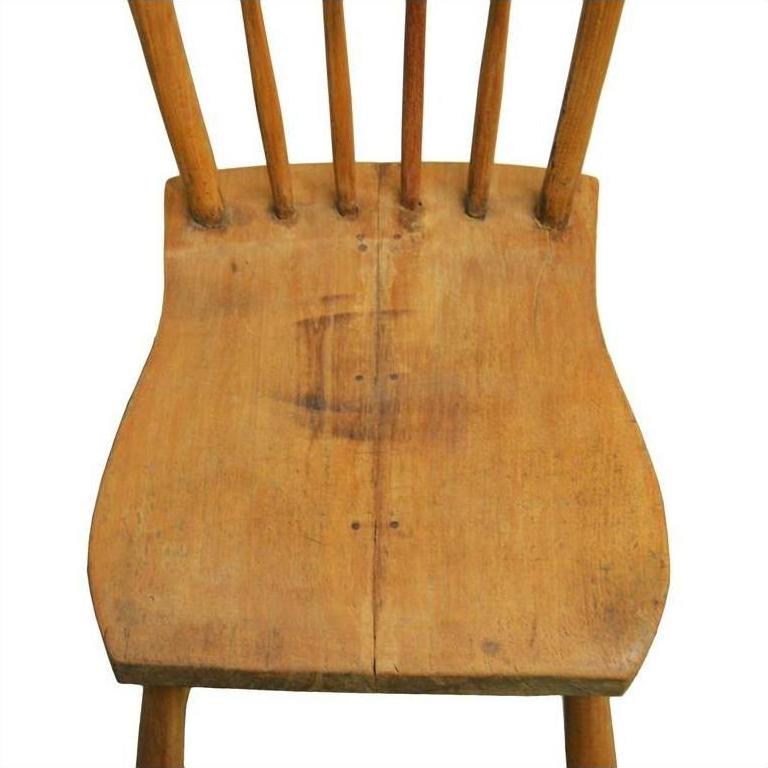 Close-up of a worn wood Indonesian chair seat with visible spindles and scratches on a white background.