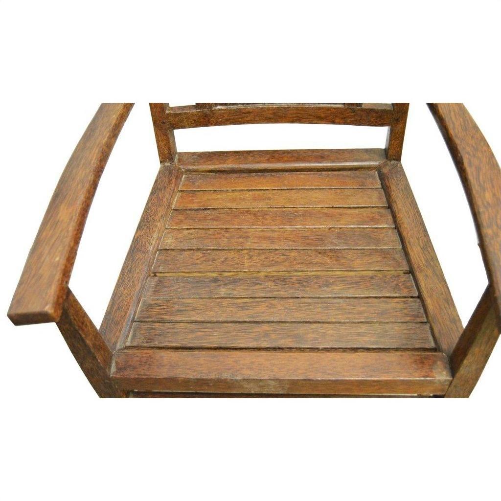 Brown wooden Indonesian Java chair with slatted seat, armrests, diamond cut-out, on white background, top view.