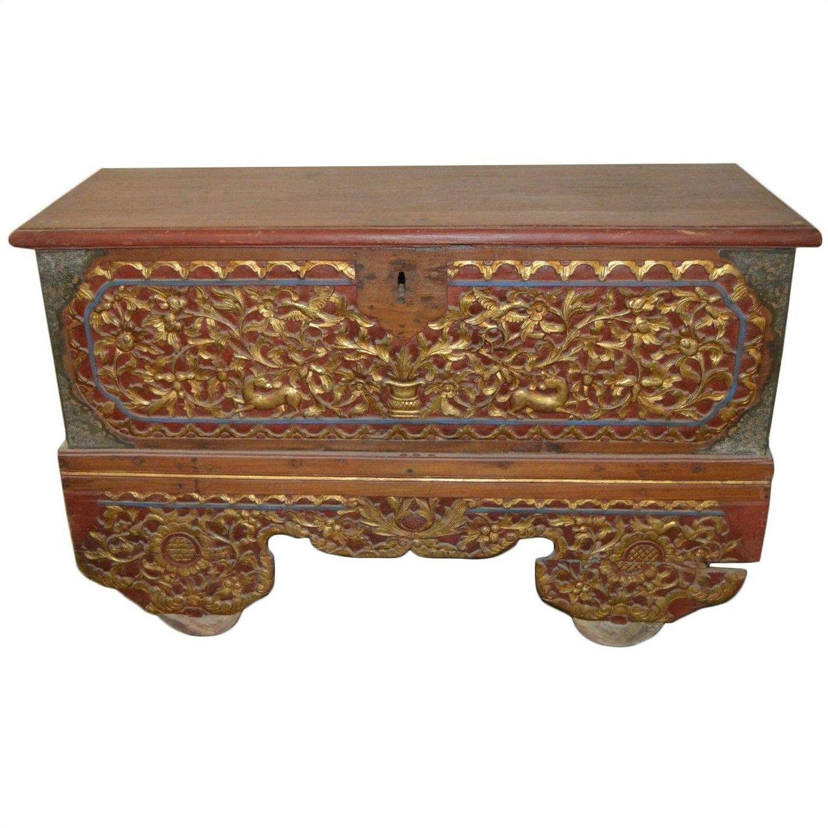 Brown wood Indonesian Madura blanket chest with ornate carvings and gold floral patterns on front and base.