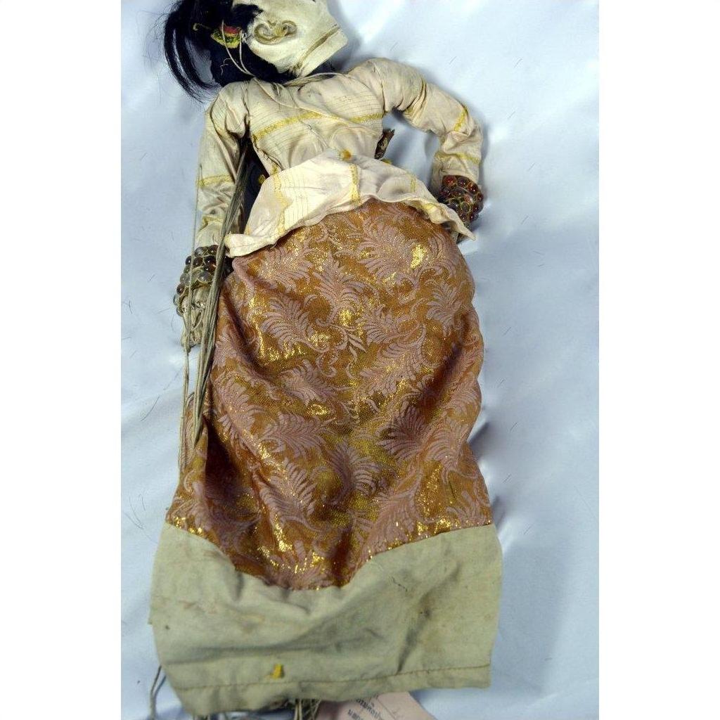 Brown and beige Indonesian puppet made of wood, with articulated fingers and movable mouth, lying on white background.