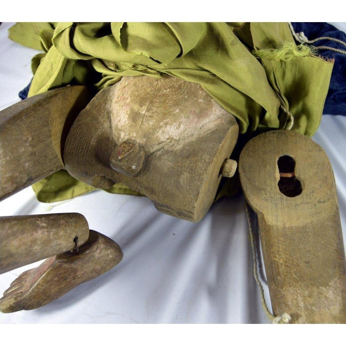 Close-up of Indonesian puppet with movable joints, loose leg, green and blue fabric clothing.
