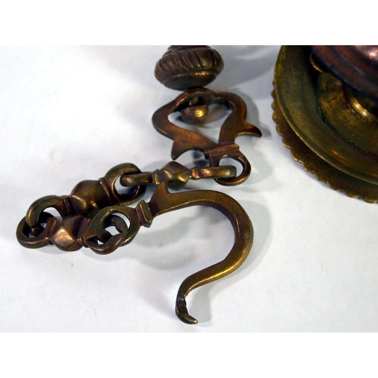 Close-up of vintage brass Japanese temple incense burner hook and chain with decorative detailing.