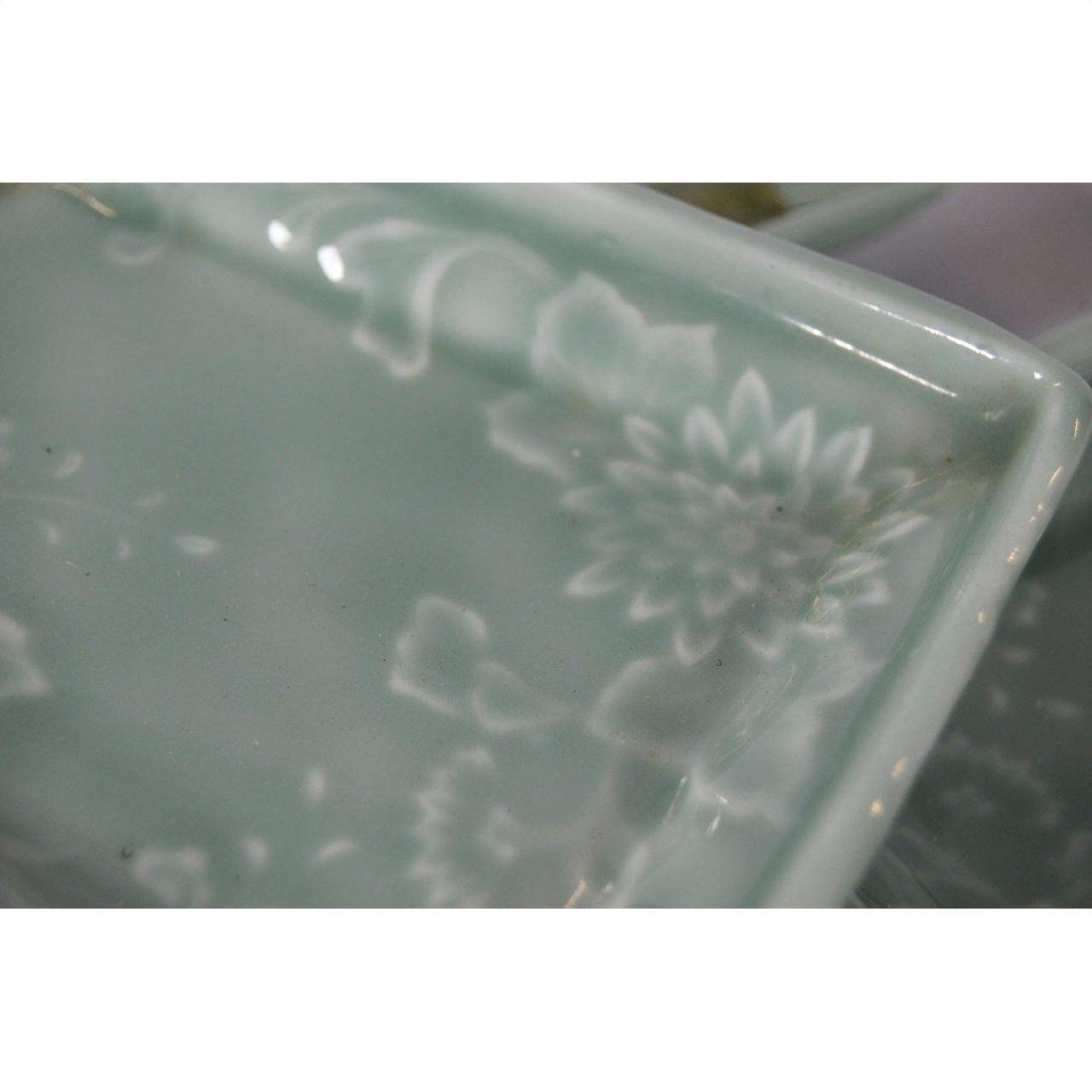Close-up of a pale green rectangular Japanese celadon serving bowl with floral pattern.