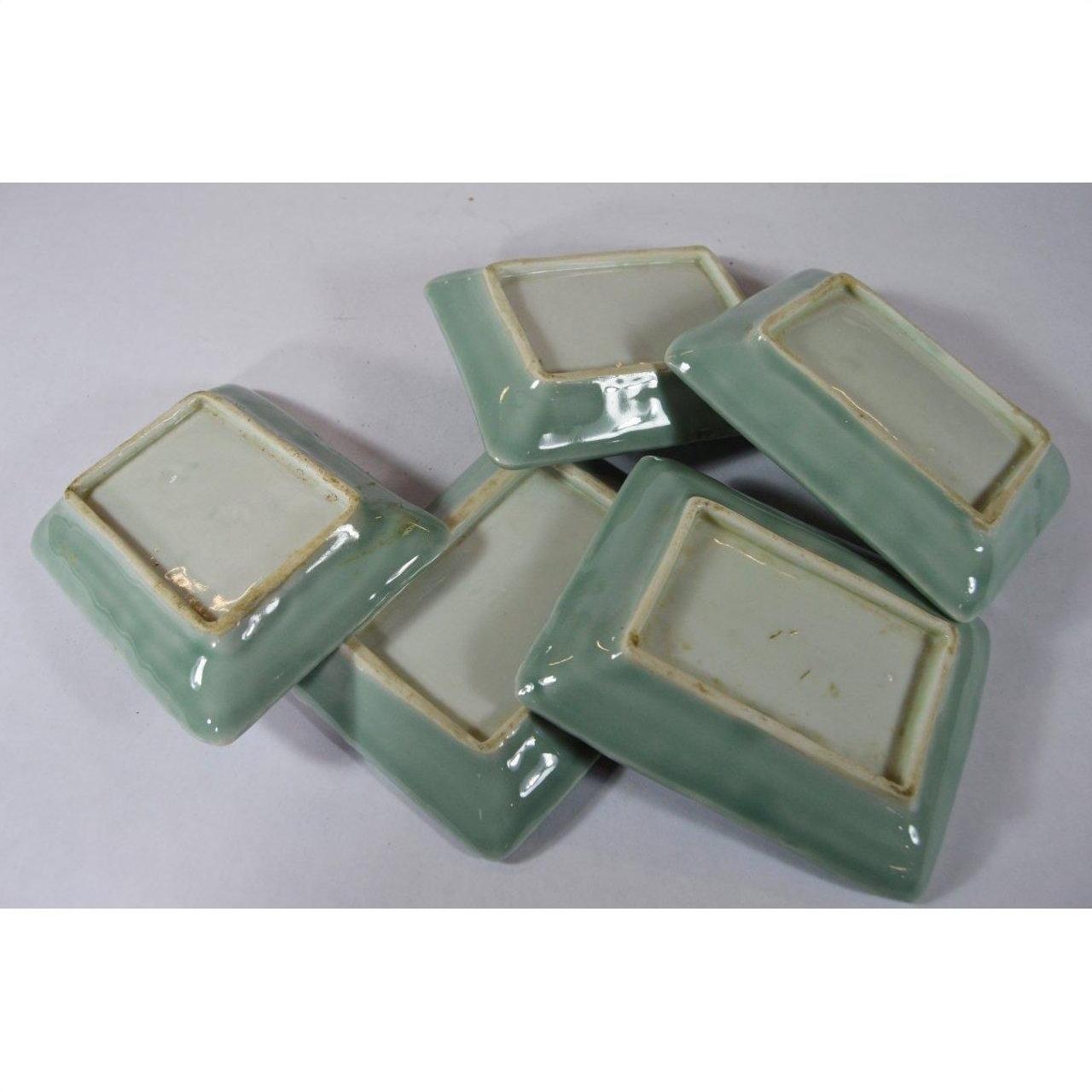 Green celadon ceramic bowls stacked, bottom view, on a white background.