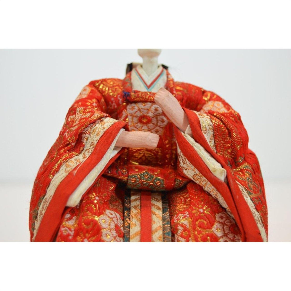 Close-up of a Japanese doll in a red kimono with gold and orange patterns, Kyoto made.