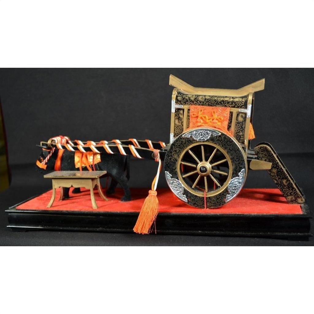 Red and black lacquered Japanese festival carts with ornate details and orange cords displayed on a red platform.