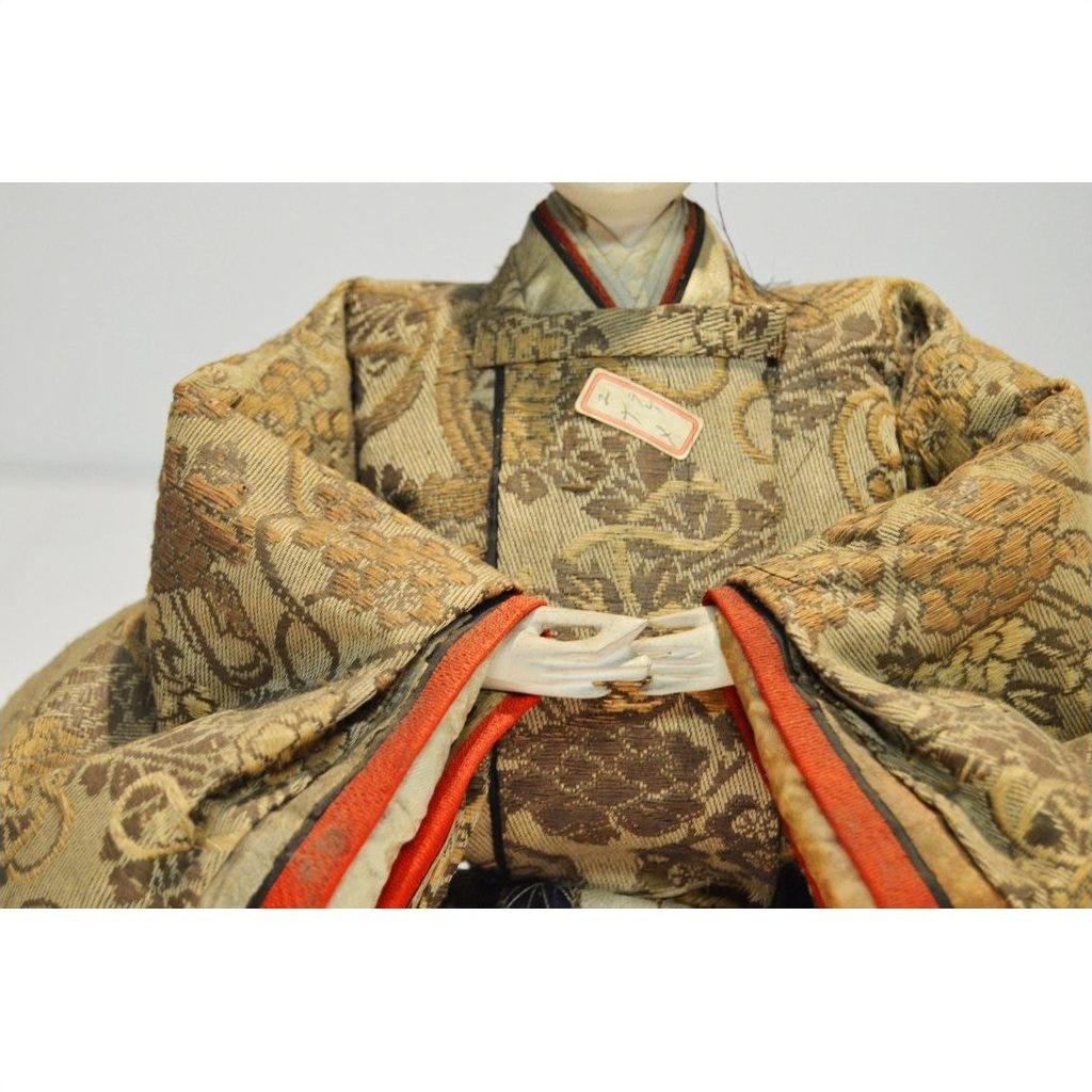 Close-up of Japanese Taisho Samurai Doll in ornate gold and brown patterned kimono with folded hands.