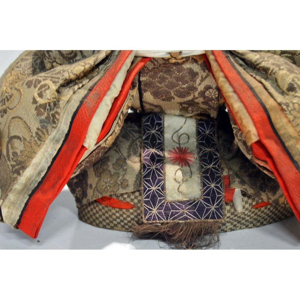 Close-up of red, gold, and purple patterned fabric layers on Japanese Taisho Samurai Doll.