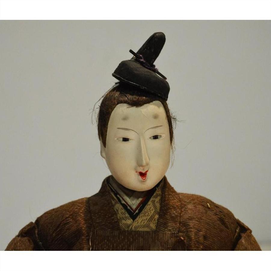 Close-up of Japanese Taisho samurai doll with painted face, topknot hairstyle, and brown kimono.