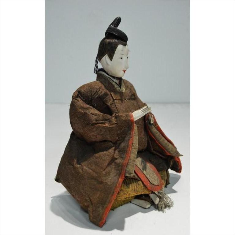 Close-up of Japanese Taisho Samurai Doll in ornate brown and red robes, seated with hands together.