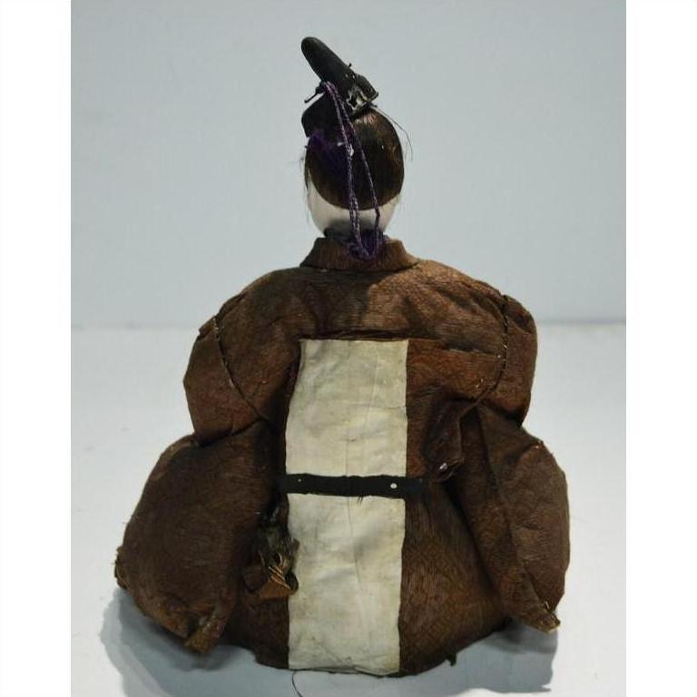 Brown fabric Japanese Taisho Samurai doll with black hat, back view, plain background.