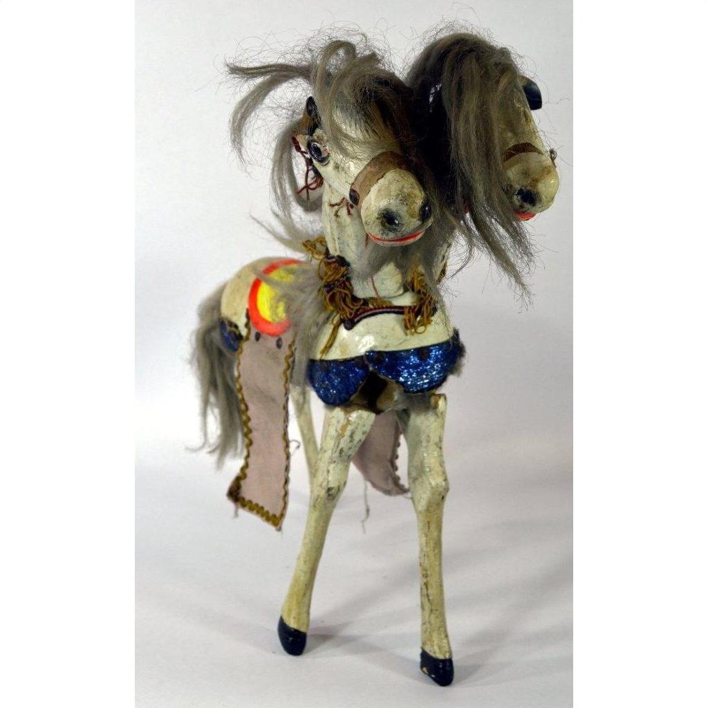 Close-up of Japanese two-headed horse toy with messy gray hair, blue sequin saddle, and decorative harnesses.