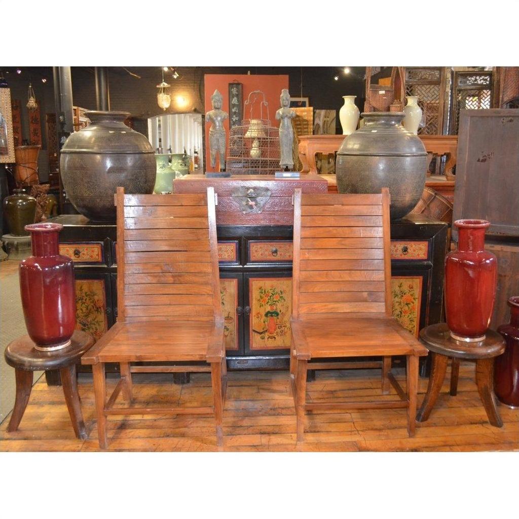 Java teak side chairs with small tables and red vases in front of a decorated cabinet in an antique shop setting.