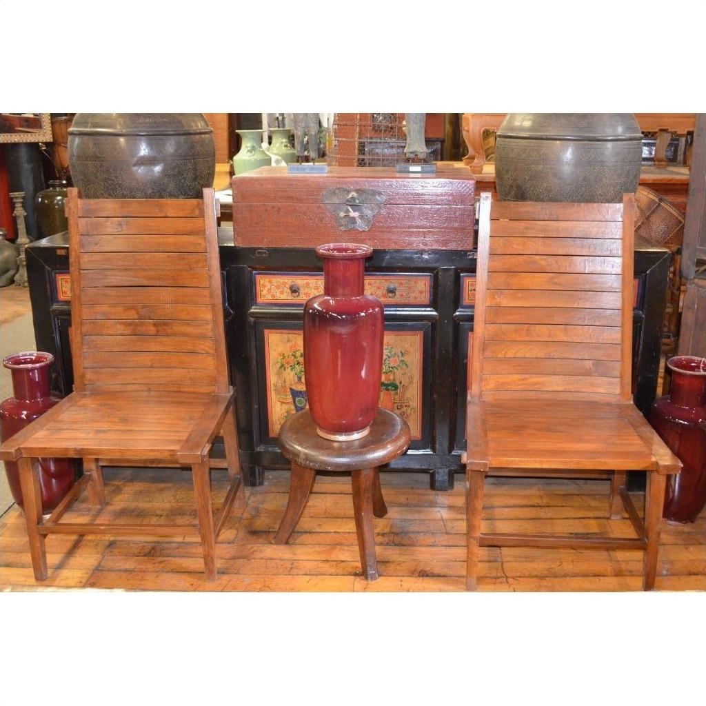 Brown teak side chairs and a small round stool with a red vase, set against cabinets and pottery in the background.