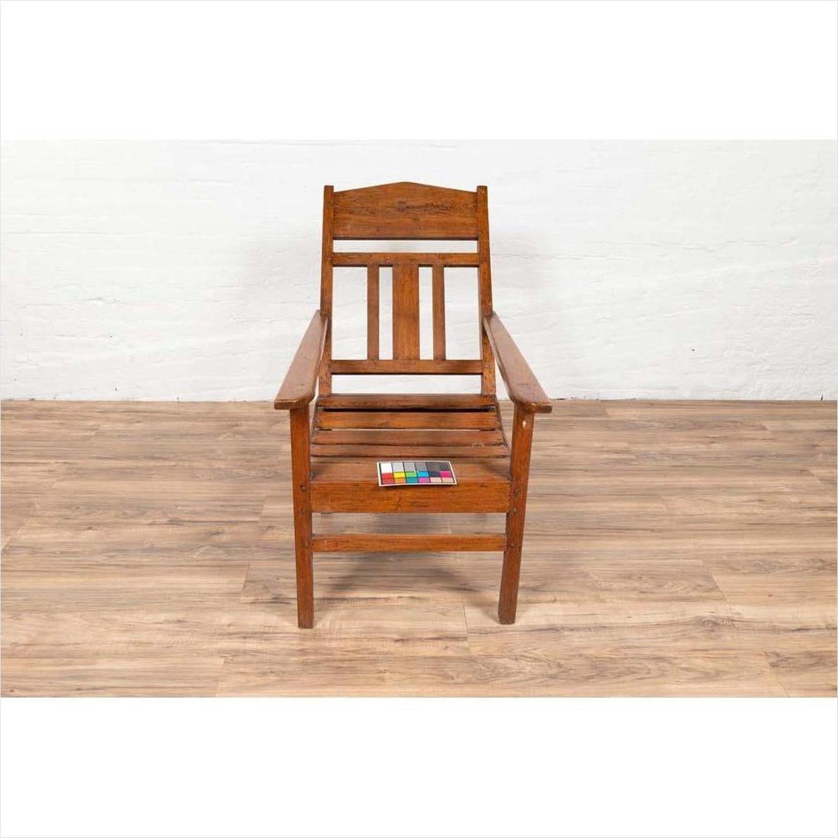 Brown wooden lounge chair with slanted back on wooden floor, color card placed on seat, indoor setting.