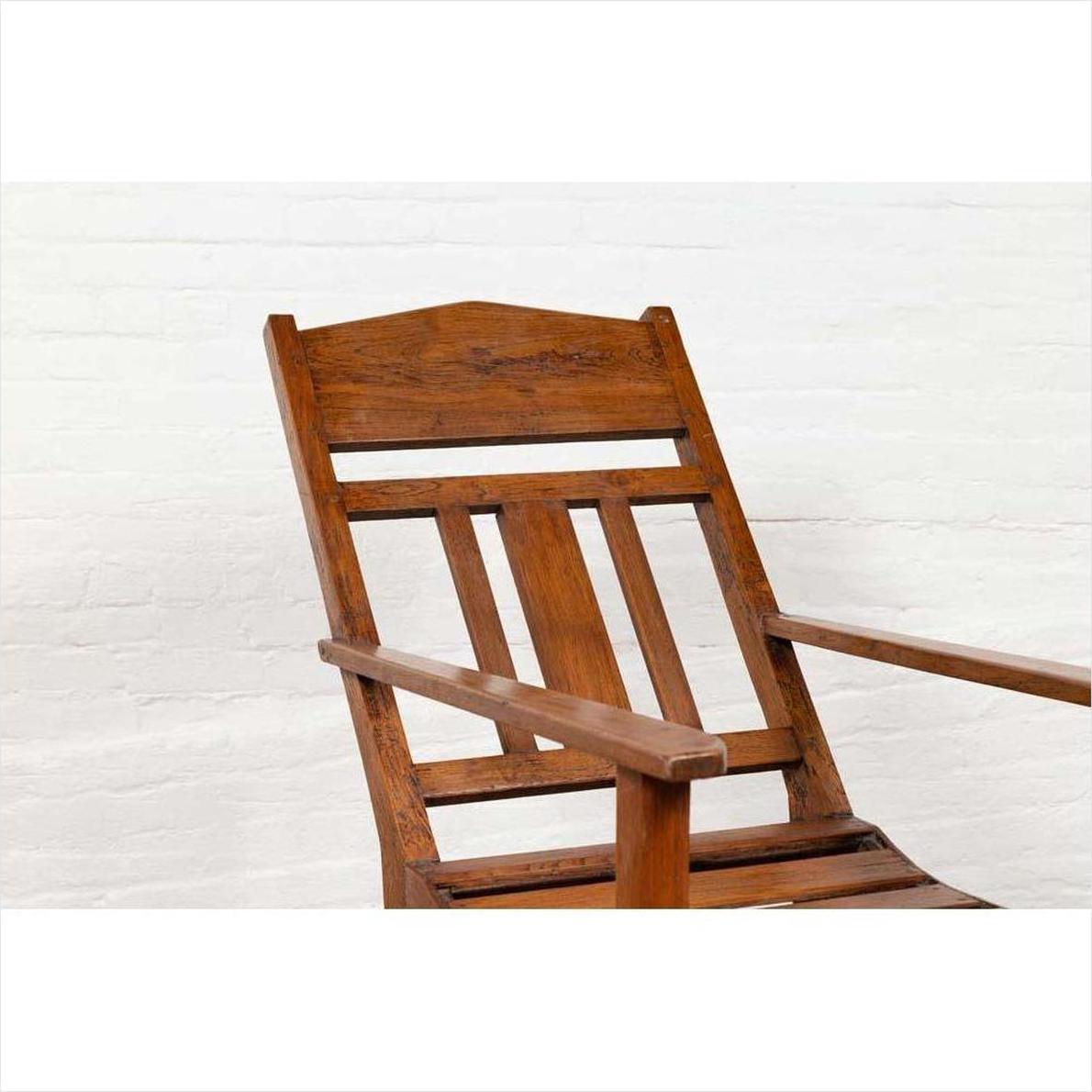 Brown wooden lounge chair with slanted back near a white brick wall, indoors.