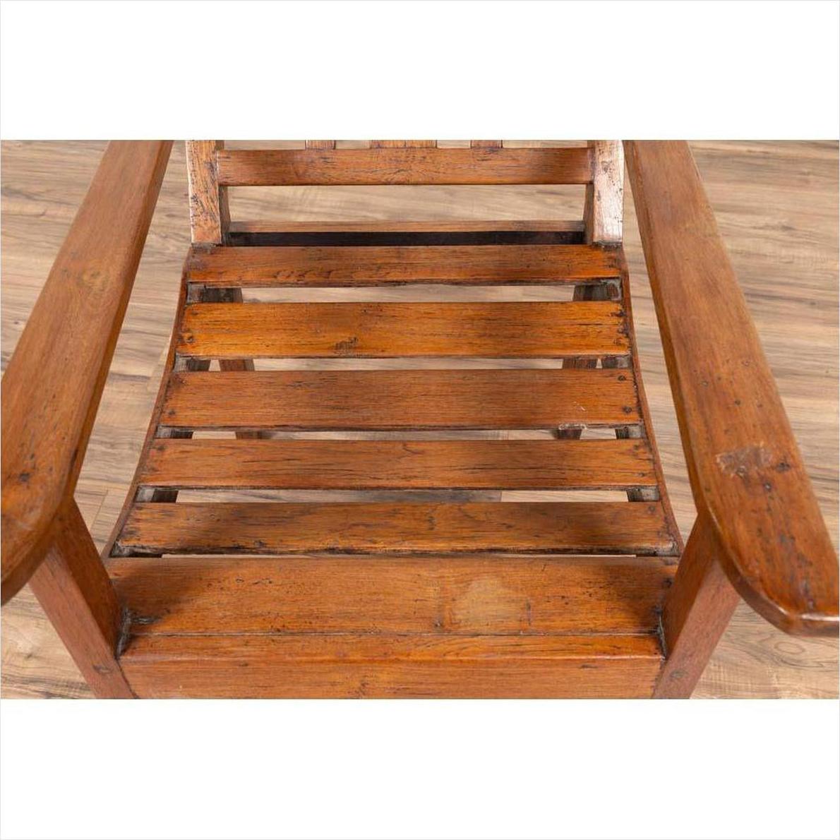 Brown wooden lounge chair with slanted back on wooden floor.