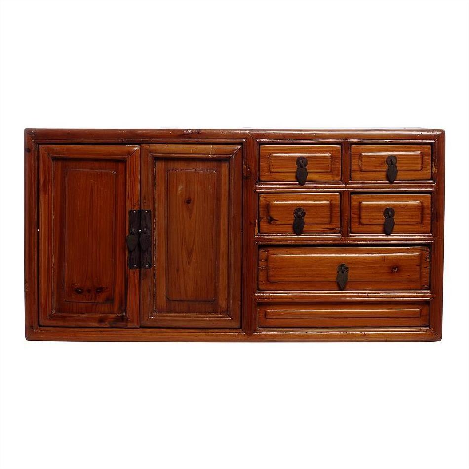 Brown wood jewelry box with one large left door, five right drawers with metal handles, close-up on table.