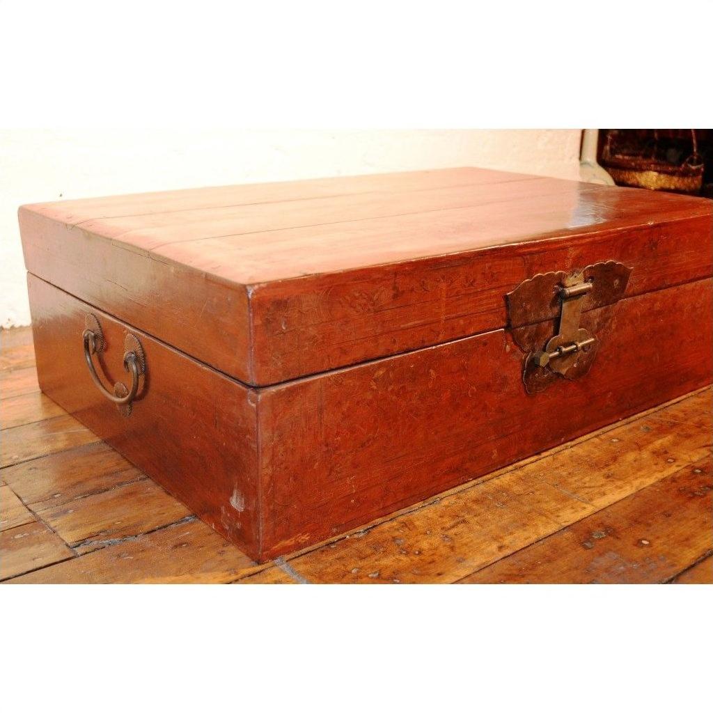Black lacquer leather trunk with butterfly hardware and metal handles on a wooden floor.
