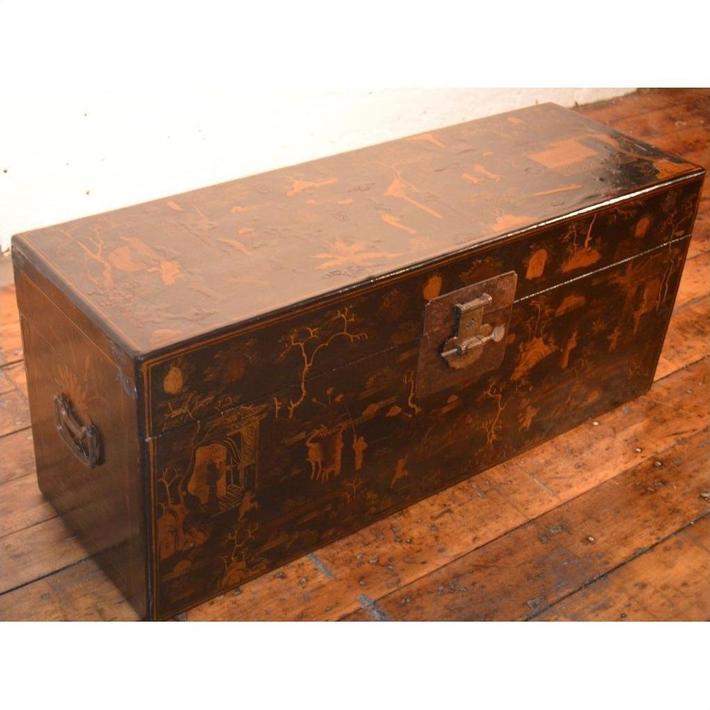 Black lacquer trunk with metal latch and painted designs on a wooden floor.