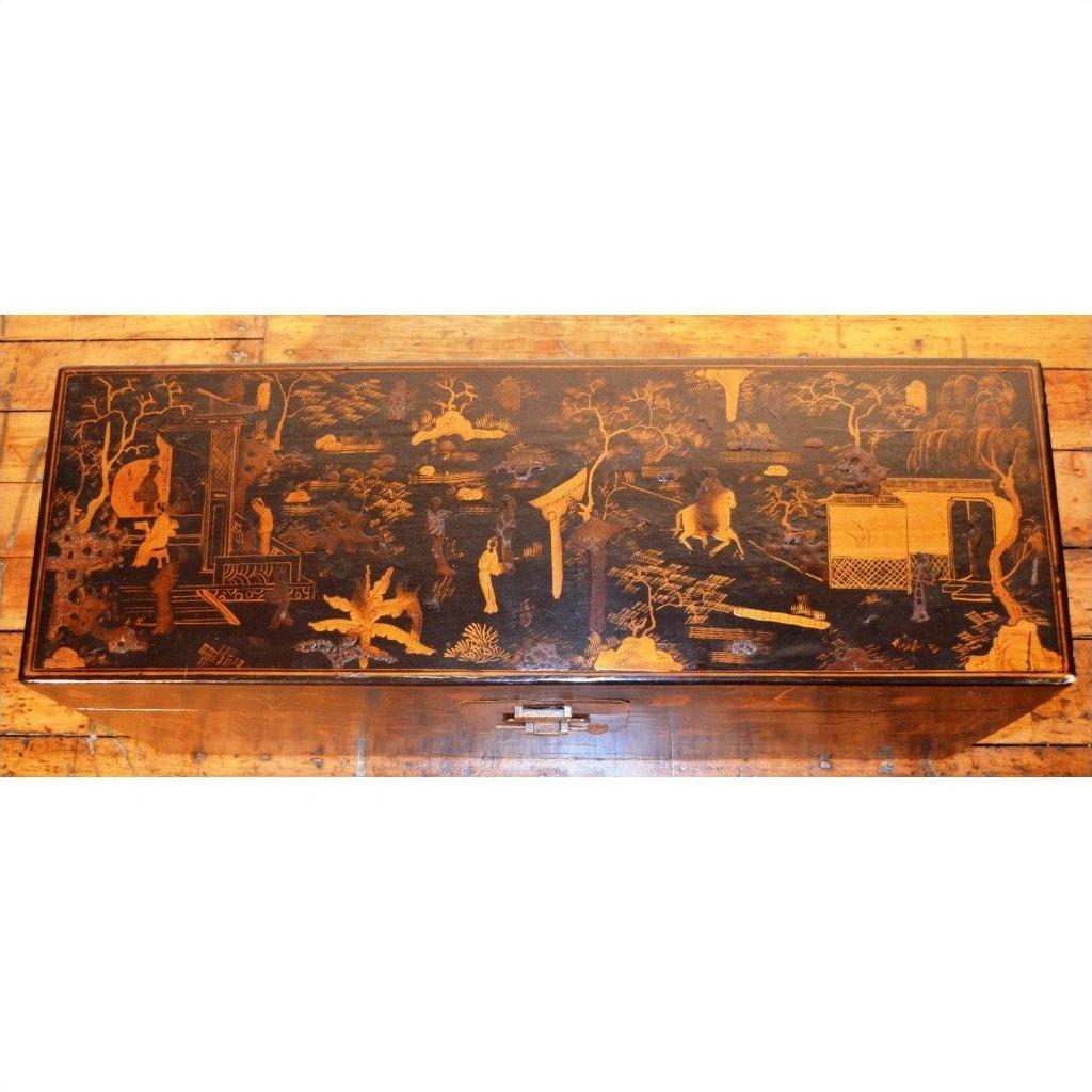 Black lacquer rectangular trunk with gold Asian landscape design on lid, displayed on a wooden floor.