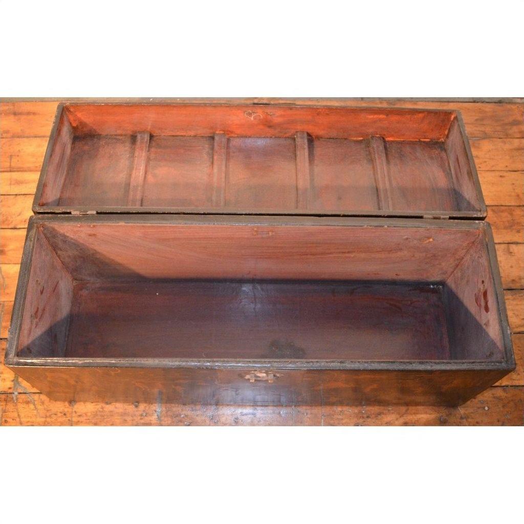 Black lacquer trunk with lid open, showing empty interior, placed on a wooden floor indoors.