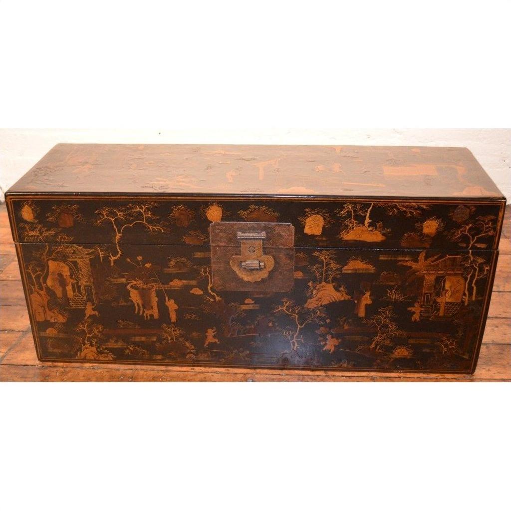 Black lacquered wood Chinese trunk with intricate designs and metal clasp, placed on a wooden floor.