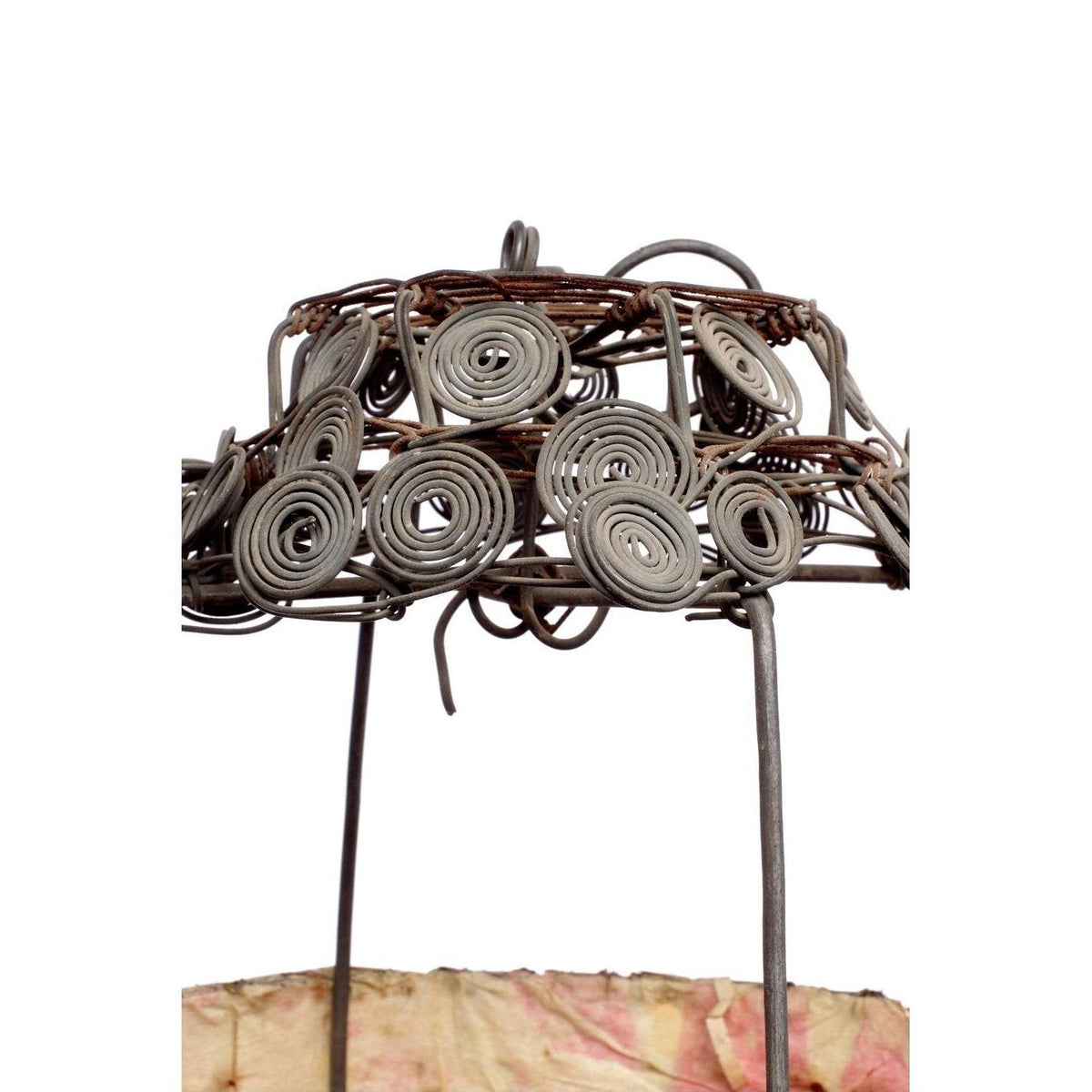 Close-up of a wire frame lantern with spiral design, draped in pink and beige fabric.