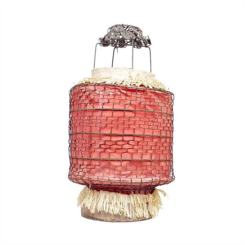 Close-up of a pink wire-wrapped cylindrical lantern with straw accents and metal top, styled like a Chinese paper lantern.