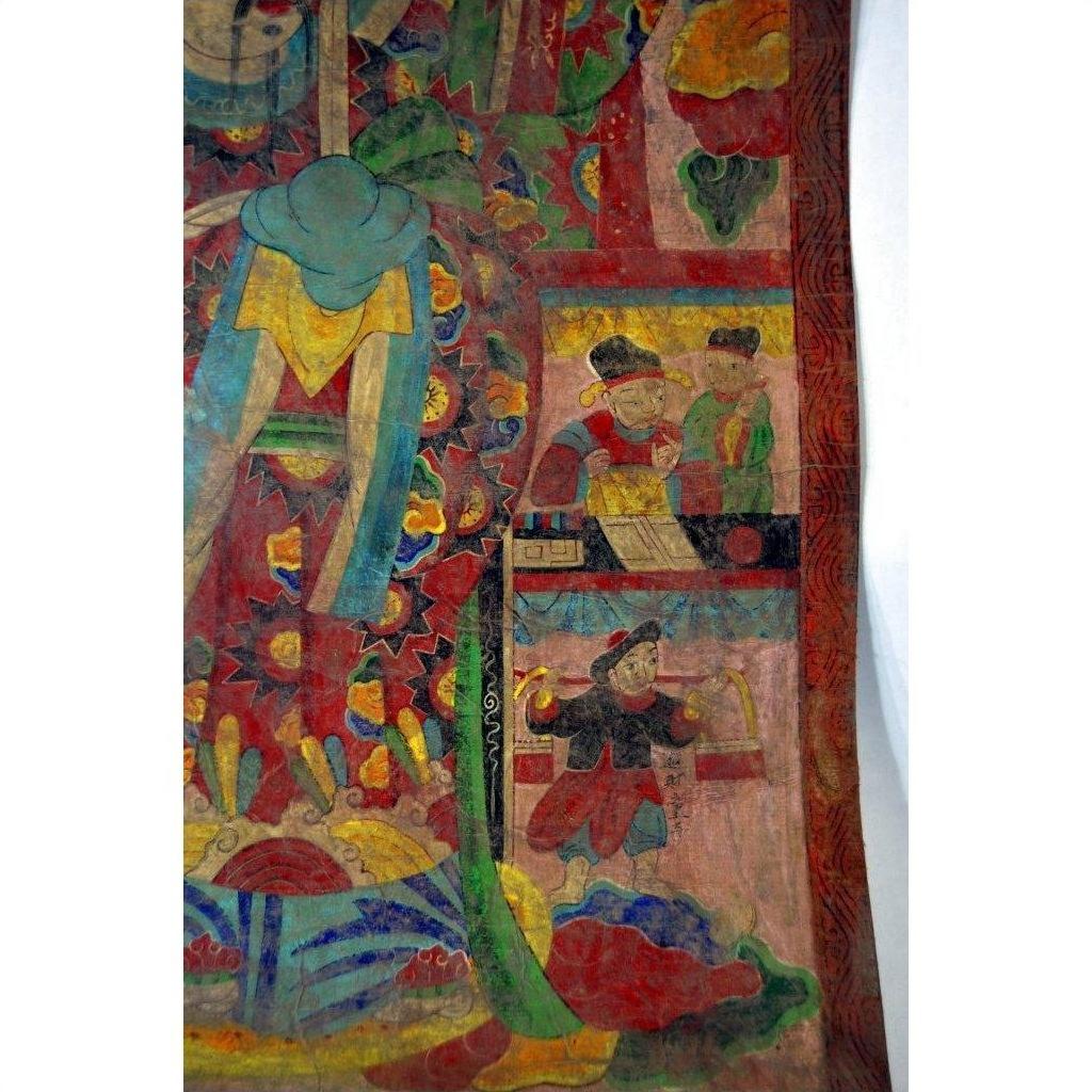 Colorful Laotian parchment painting with people and ornate patterns, displayed in a double plexiglass frame.