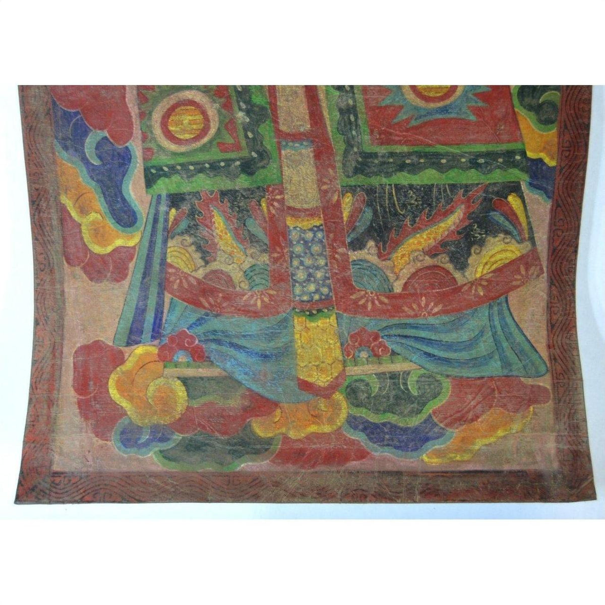 Multicolored Laotian parchment painting with ornate clouds, red, green, yellow, and blue accents, close-up view.