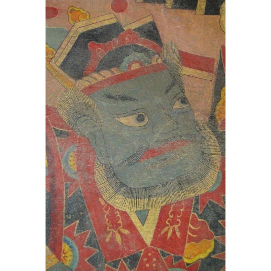 Close-up of Laotian parchment painting showing a stern green-faced figure in ornate robe and headdress.