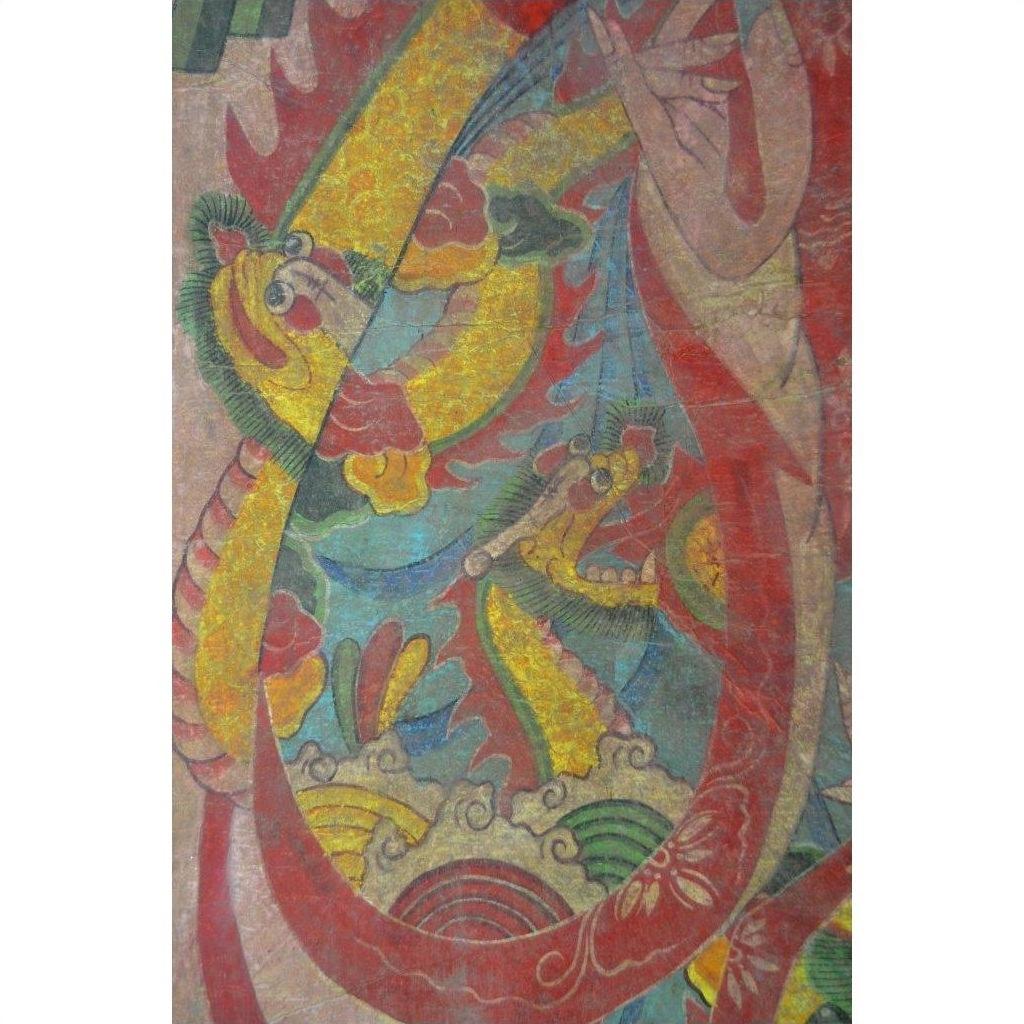 Bold red, yellow, and green Asian dragon painted on Laotian parchment with swirling clouds, close-up view.