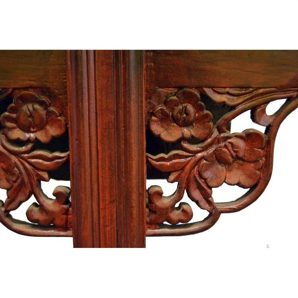 Close-up of antique elm wood altar table with stained finish and detailed carved floral designs.