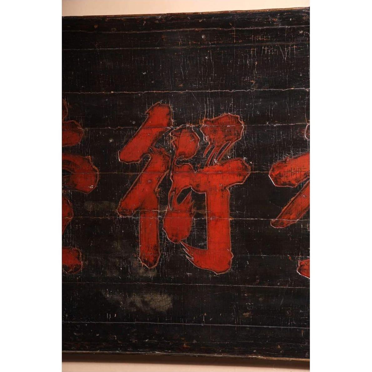 Close-up of dark wood Chinese signboard with bold red Chinese characters, weathered 19th century surface.