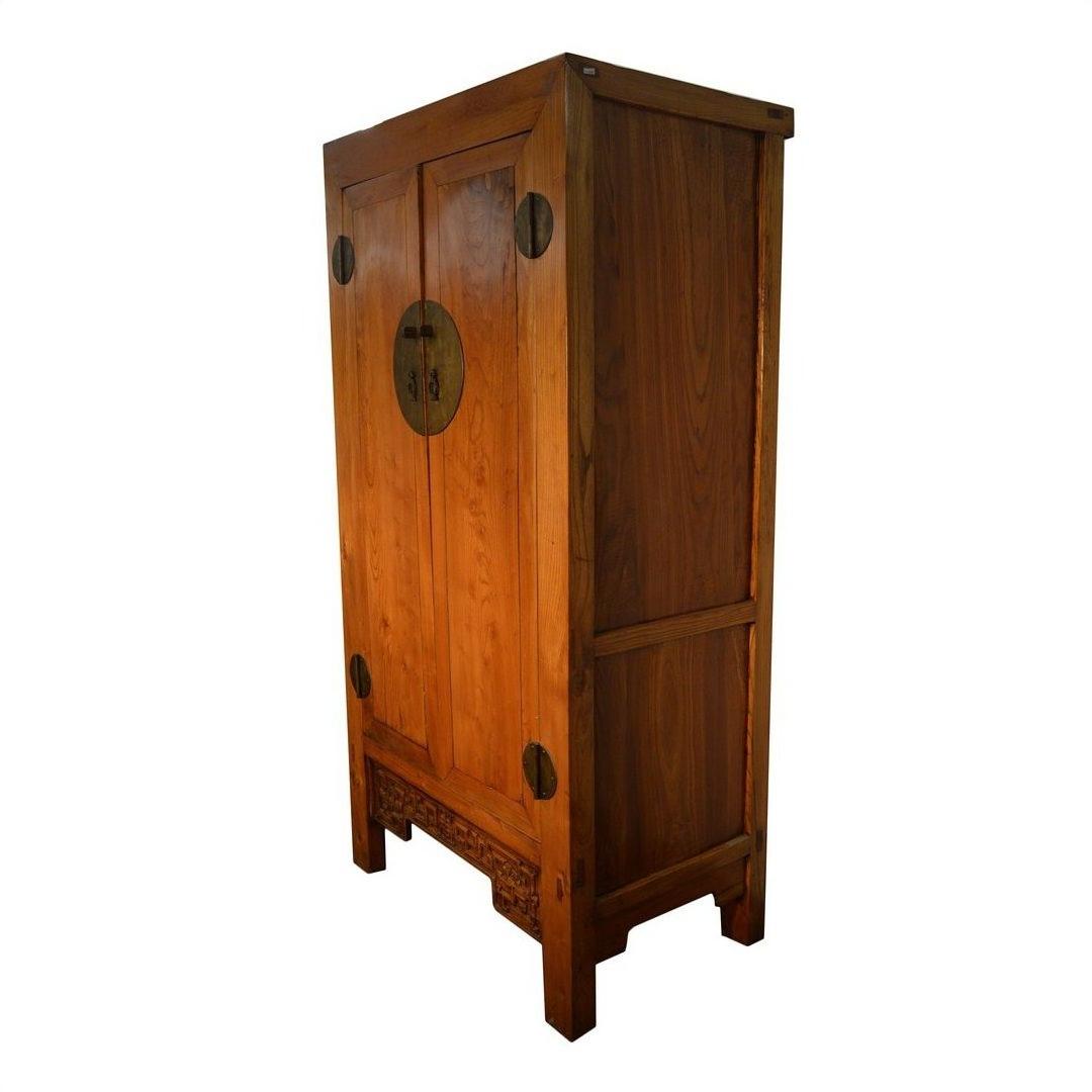 Brown wood armoire with carved panel doors, ornate metal handles, and decorative carved legs, front view.