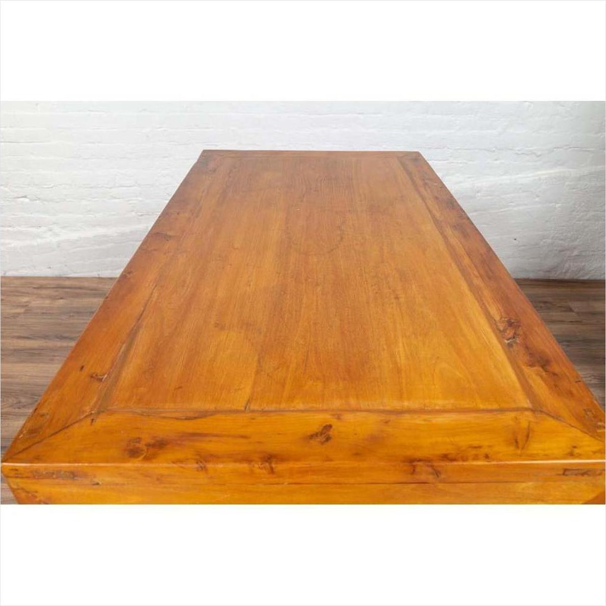 Two-toned brown burl and elm wood antique cabinet beside rectangular wooden table, indoors against white wall.