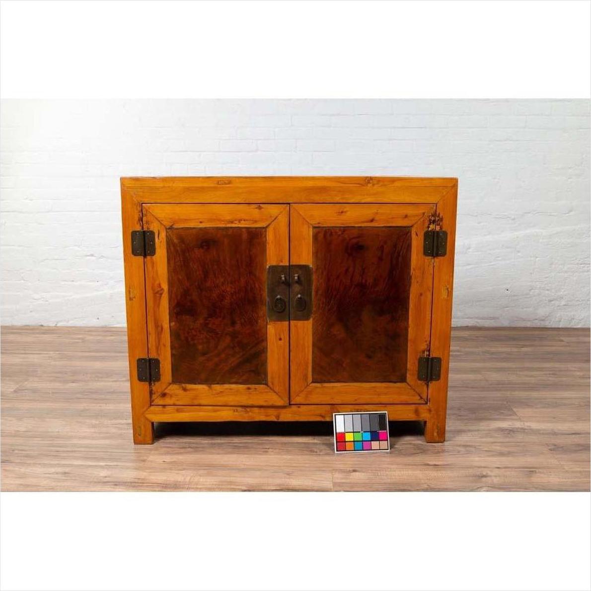 Brown burl and elm wood two-toned patina cabinet with doors, shown on a floor with a color chart in front.