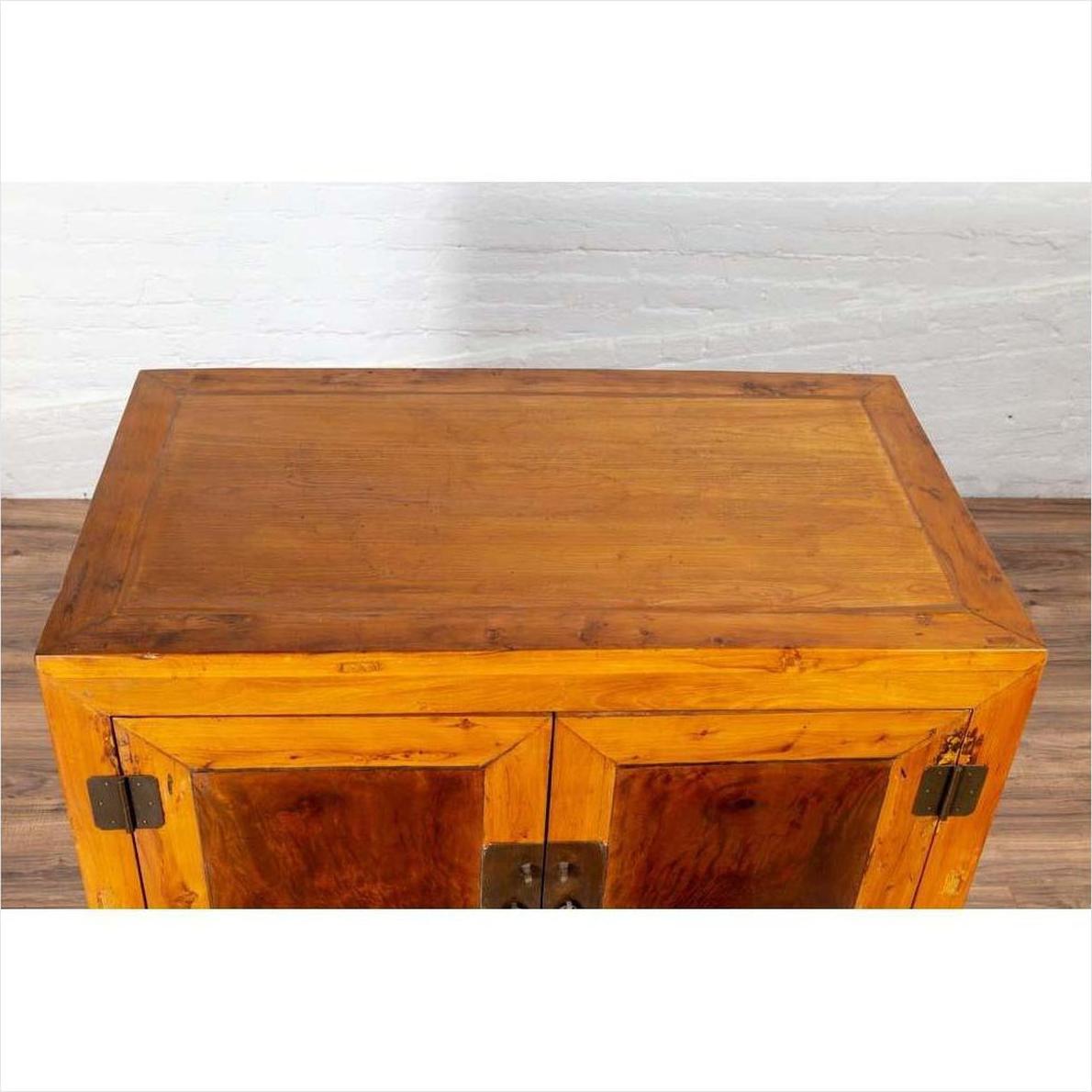 Brown burl and elm wood cabinet with doors, antique style, positioned indoors against a white brick wall.