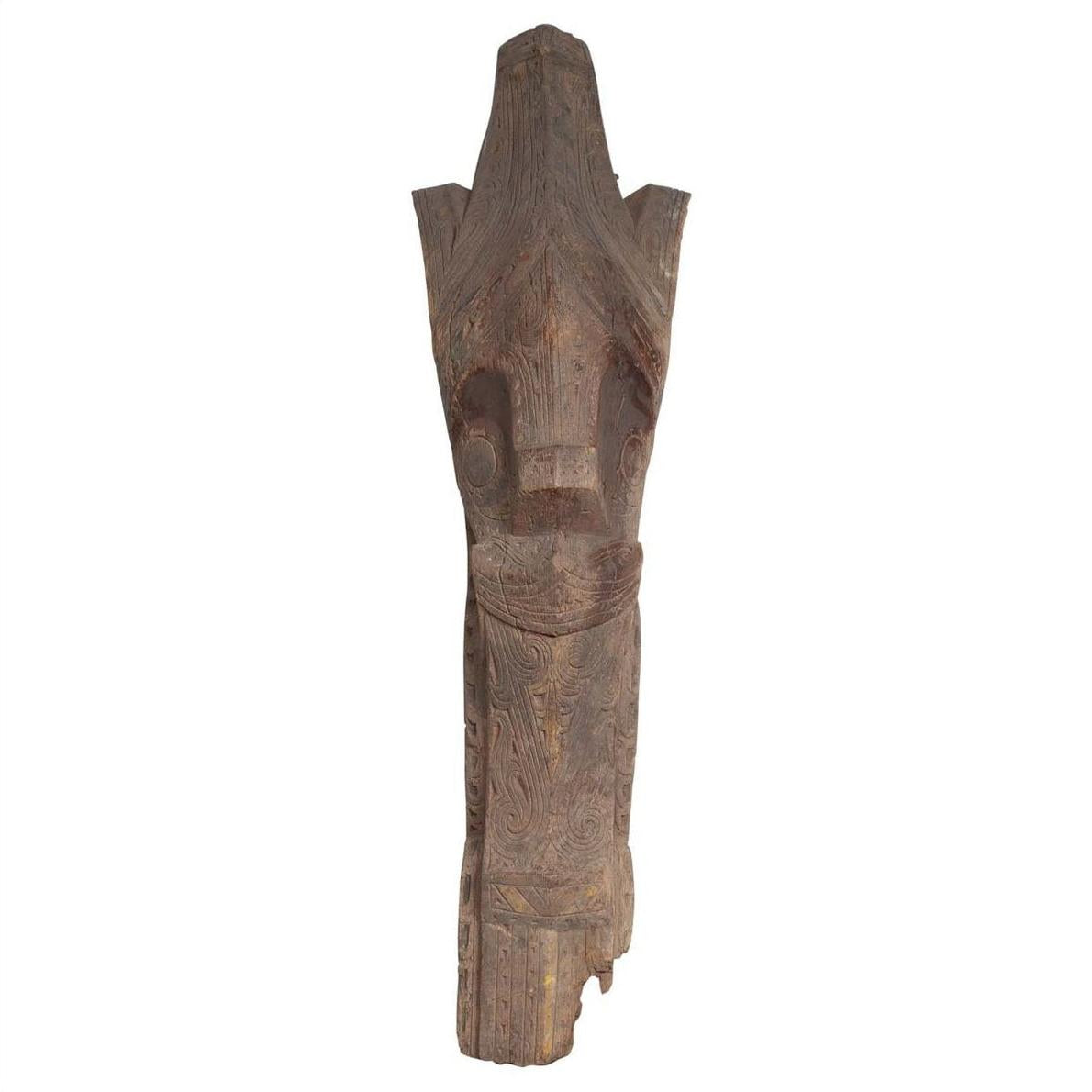 Close-up of brown hand carved wooden Batak Singa Singa tribal carving from Sumatra with intricate swirl patterns.