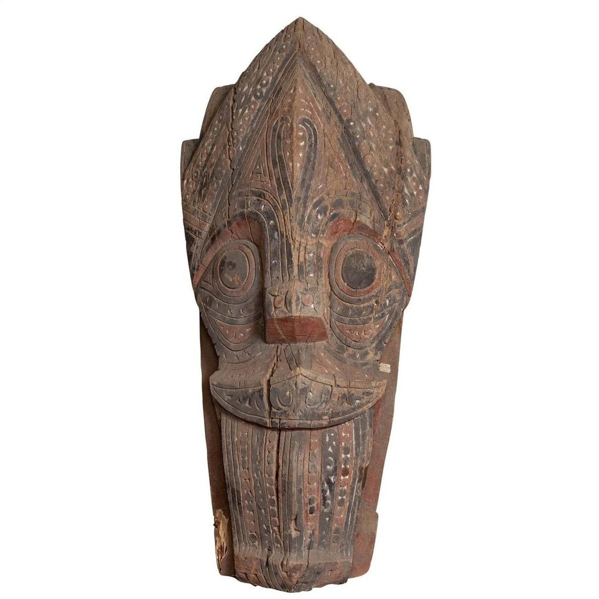 Brown hand-carved wood Singa Singa tribal statue with intricate patterns, Batak people, Sumatra, close-up view.