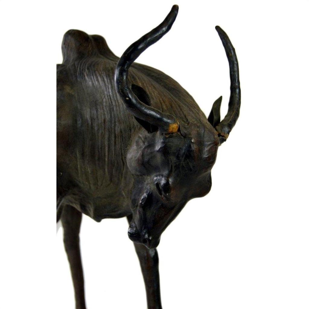 Brown leather gnu sculpture with curved horns and lowered head against a white background.