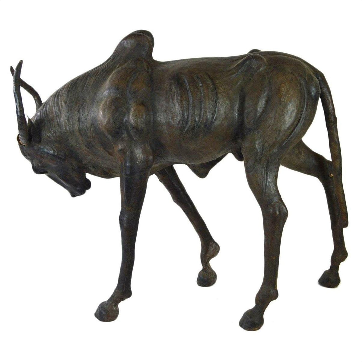 Brown leather wildebeest sculpture with head lowered and legs bent, placed on a plain surface.