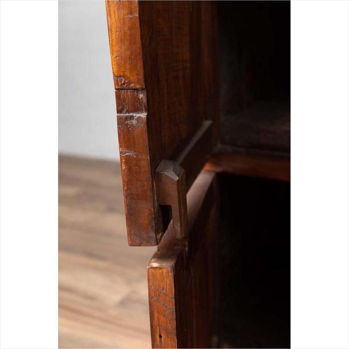 Close-up of brown teak wood joint on large cabinet with four drawers and four double doors.