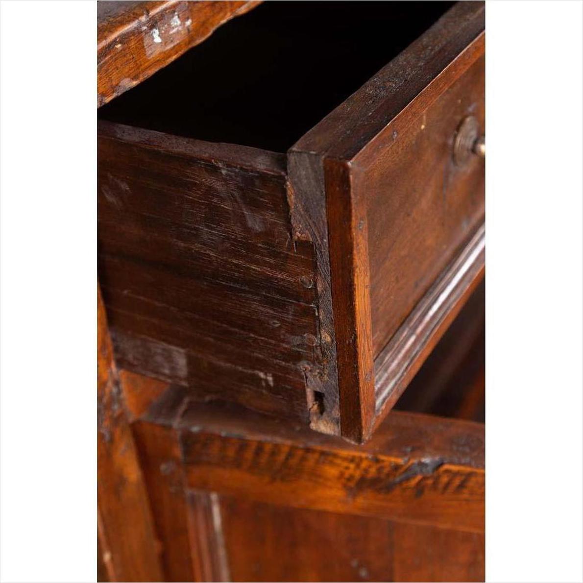 Close-up of brown teak wood cabinet with open drawer, showing visible scratches and wear.