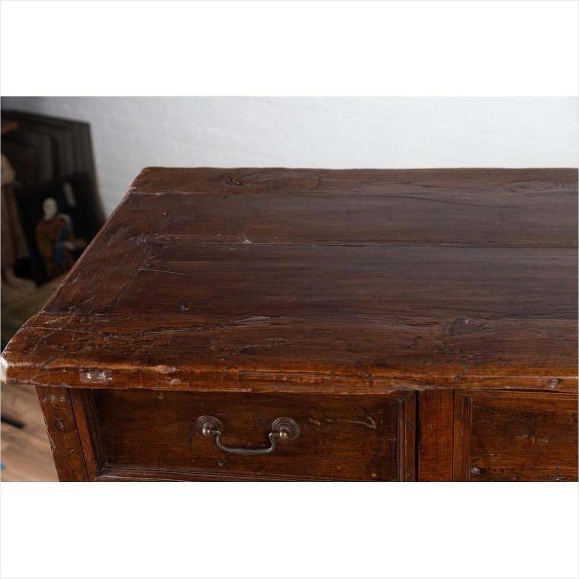 Close-up of a brown teak cabinet with four drawers and four double doors, vintage details visible.