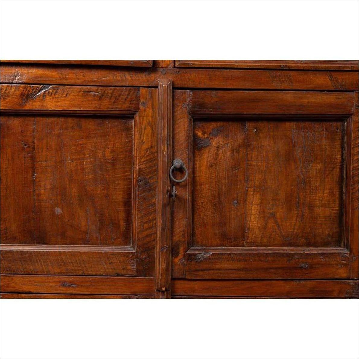 Close-up of brown teak wood cabinet with ring-shaped metal handles and visible wood grain on double doors.