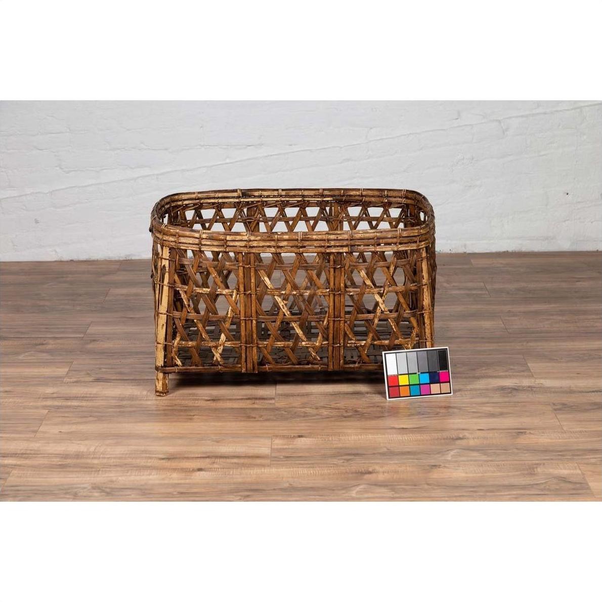 Large vintage Thai bamboo fretwork basket, natural color, on wooden floor next to a color calibration card.